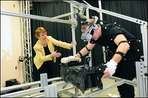 Allison Stephens, an ergonomics engineer at Ford's campus in Dearborn, Mich., monitors her colleague Glenn Harrington, fitted with motion-capture receptors, as he reproduces the movements required to install a center console in a Fusion midsize sedan. 