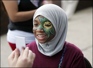 CTY birmingham16p  Sayedah (cq) Rashad (cq), 13, of Toledo, checks out the face painting wotk of Amber Lefever, [not pictured] of Bowling Green, who is holding the mirror for her. The 36th annual Birmingham Ethnic festival, centered in St. Stephen's parish, in east Toledo, Ohio on August 15, 2010.  The Blade/Jetta Fraser