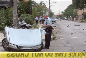 A Toledo Police officer examines the front third of the car as it rests in the intersection of Broadway and Walbridge. The back part can be seen in the background stuck in the bushes.<br>
<img src=http://www.toledoblade.com/graphics/icons/photo.gif> <font color=red><b>VIEW GALLERY:</b></font> <a href=