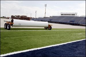 With damaged school buildings in the distance, a synthetic surface is installed at Lake Community Stadium. The cleanup and new field were completed in only two months.
