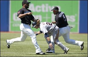 Detroit's Will Rhymes, center, is caught between Toronto's Edwin Encarnacion, left, and Yunel Escobar in the first inning. 