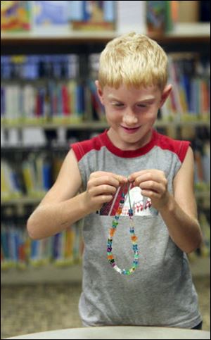 Zach Murdock, 6, of Petersburg puts the finishing touches on a necklace.  
