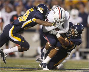 University of Toledo players Jermain Robinson, left and Mark Singer, right, wrap up Arizona's Juron Criner Friday night. 