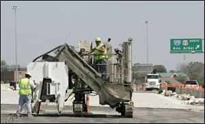 Foreman Steven Risner, left, and Eric Miller prepare a concrete-pouring machine at the Maumee project.