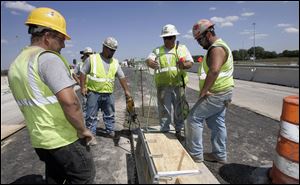 Foreman Steven Risner, second from right, confers with masonry crew members Mark Maddy, left, Steve Williams, and Donny Williams as the work on replacing the deck on  the State Rt. 24 bridge over I-475 in Maumee.
