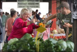 Pam Weirauch, owner of Pam's Corner on 10th Street in Toledo, buys sweet peppers from Ed Farnsel of Metamora, Ohio, at the Farmers' Market downtown.