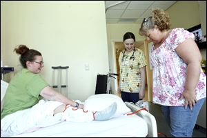 Bri Mullinger gives nurse Sarah Schwen and her mother Teri Mullinger, an update from her bed in Toledo Children's Hospital.