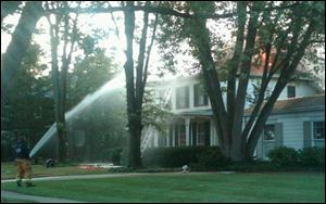 A firefighter douses flames that can be seen shooting from the roof of this home at 566 Front St. in Perrysburg.