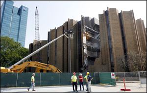Demolition crews stand outside the old United Way Building downtown as work that is to end in early October breaks exterior walls.
