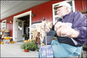 Lyle Crots of Ottawa Lake entertains orchard visitors with his musical saw, which he's been playing for 10 years.