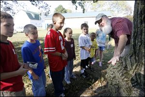 Dennis Walsh, a naturalist volunteer, describes to students from Oakdale School the characteristics of one of hte trees at the Blue Creek Conservation Area.