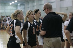 Alex Blazevich, left, and teammates Adrienne Kanitz and Lauren Hunt talk with coach Greg Reitz during Lourdes' opening volleyball game last month.