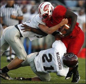 Eastwood's Pernell Conner is stopped by Genoa's Casey Wojciechowski  and another Comet in Friday night's game.