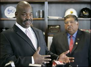 Toledo Mayor Mike Bell addresses the media Thursday following a meeting with Bob Vasquez, president of the Toledo Board of Education, back right, at One Government Center.