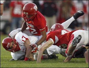 Bedford quarterback Jared Kujawa is brought down after a long run by Monroe's Reggie Allen, top, and Jakup Macmullen.
