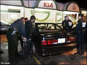 Toledo police gang unit Officer Herbert Higgins handcuffs a man outside the IGA store on Bancroft Street for possible drugs and weapons violations.