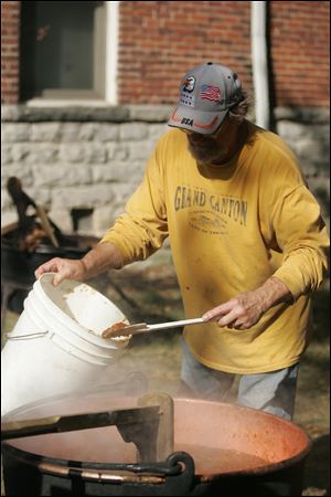 CTY butter11p  Gary Miller, of Neapolis, one of many volunteers who makes the festival happen, adding to the apple butter as it is cooked down. The Grand Rapids Applebutter Festival held on the streets of Grand Rapids, Ohio on October 10, 2010.  Jetta Fraser/The Blade