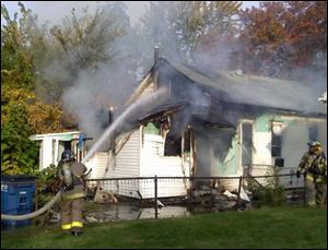 A Toledo firefighters hoses down the home on Blum Street.