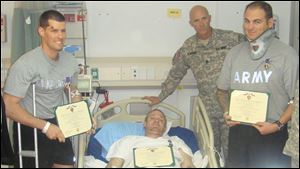 Capt. Robert L. Beat, left, sent this photograph of him holding his Purple Heart to his family in Sylvania from the hospital at Bagram Air Base
just two days
after his armored vehicle struck an improvised explosive device in Afghanistan. Captain Beat is scheduled to complete his recuperation in Germany.