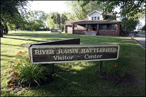 River Raisin Battlefield sign directs visitors to an information center. The site is along East Elm Avenue.