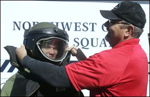 Owens Community College instructor Mike Nearhood adjusts the helmet of the uniform worn by a bomb disposal unit member on Tyler Blohm of Fremont Ross Tech Center.