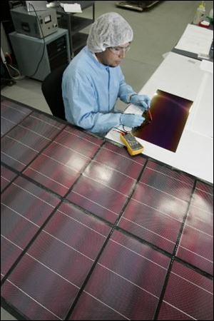 A technician at Xunlight Corp. tests voltage emitted by a solar panel. The Toledo company received a $34.5 million federal tax credit early this year. 