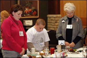 At this season's local gathering of Mayflower descendants and their spouses, Ashley and Blake Kaylor, left, of Woodville and June Chapin, right, of Fremont bow their heads in prayer at the table.