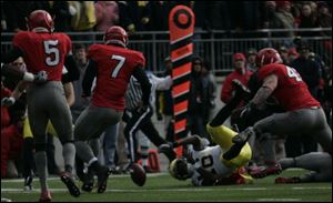Michigan's Denard Robinson fumbles to stop an early scoring opportunity. The Wolverines turned the ball over three times.