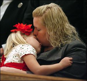 Slug: CTY XMASPIC24 01  The Blade/Jeremy Wadsworth  Caption: Amy Firsdon of Oregon, Ohio, comforts her daughter Samantha, 6, Friday, 12/24/10, during the Christmas Eve Mass at the Rosary Cathedral in Toledo, Ohio. Bishop Leonard Blair is the celebrant.