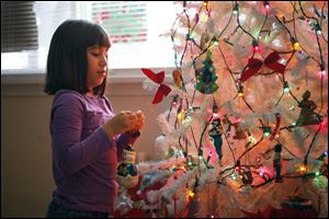 Six-year-old Angel adds an ornament as she prepares for her first Christmas in the home of Mark and Cyndi Wright. They took her in last April after Lucas County Children Services contacted them. Angel's mother is a second cousin to Mrs. Wright.