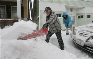 Delton Opfer, center, his 13-year-old granddaughter Vanessa Skouroukos, right, and his 15-year-old grandson John Skouroukos VI, who is almost obscured at back left, clear snow from their sidewalk and around their car in East Toledo.