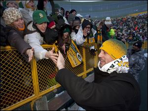 Aaron Rodgers, followed at right by cornerback Charles Woodson, greet loyal followers at Lambeau Field.