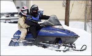 Ashly Studyvin of Maumee hangs on to boyfriend Zachary Gramling of Henry County's Colton area as they zip about Liberty Center during last week's snowstorm.