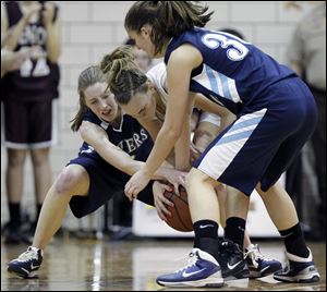 Lake's Kaysie Brittenham, left, and Carly Huston, right, battle for the basketball with Genoa's Julie Swartzmiller. Brittenham and Huston each scored 11 points to lead the Flyers to another SLL title.