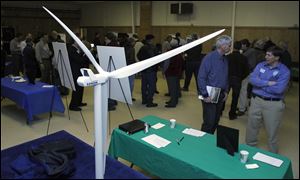 A model of a wind turbine is displayed as residents chat with members from the Blissfield Wind Energy project team during an open house. In the foreground are John Richey, left, and John Bulloch.