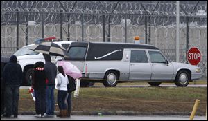 A hearse carrying the remains of Johnnie Baston passes by a group of death penalty opponents as it leaves the Southern Ohio Correctional Facility after his execution.