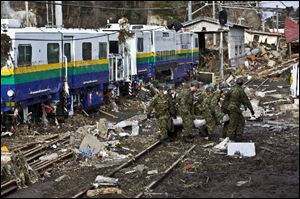 Members of the Japanese Defense Force remove the body of a victim of last week's tsunami from what remains of Nobiru station in Miyagi, Japan.