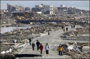 People walk a road between the rubble of destroyed buildings in Minamisanriku town, Miyagi Prefecture, northern Japan, on Monday, three days after a powerful earthquake-triggered tsunami hit the country's east coast.
