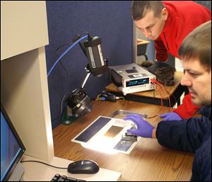 Scientist Victor Plotnikov, left, and technician John Stayancho measure the performance of a solar module using a solar simulator.