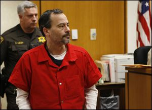 John Skelton, shackled as he walks into the Lenawee County Circuit Courtroom, fixes his eyes on his wife. 