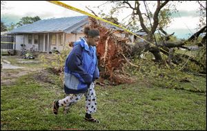 Marcie Moore walks Tuesday near a downed tree in Jackson, Ga. Her 4-year-old son, Alix Bonhomme III, was killed along with his father Alix Bonhomme Jr. in the severe storm that whipped across the South. 