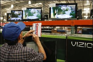 A shopper notes television prices at the Costco Wholesale store in Glendale, Calif.