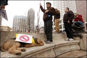 Dennis Brinton, a retired public employee from Cuyahoga Falls, a northern Akron suburb, has his dog Jack outfitted with a sign opposing Ohio Senate Bill 5 on the west lawn of the Ohio Statehouse on Saturday. The bill was signed by Gov. John Kasich more than a week ago.