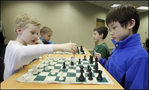 As part of chess club activities at Ottawa Hills Elementary School, Nick Mack, 8, left, makes a move as his opponent, Peter Wu, 10, watches. Also playing are Gareth Francis, 8, back left, and Max Bishop, 8.