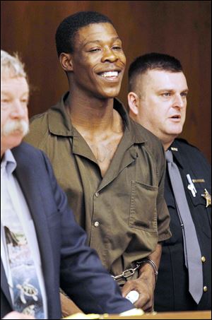 Thomas Johnson, center, smiles as he crumples a  piece of paper during his arraignment in Toledo Municipal Court.