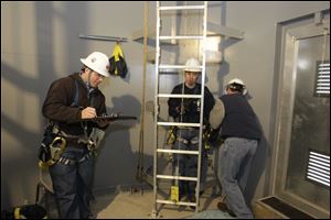 Instructor Nate Eaton, left, a Local 8 member, notes the finish time of Derrick Martin of Norwalk, center, as instructor Ray Struffolino, another Local 8 member, removes weight added for the climb. 