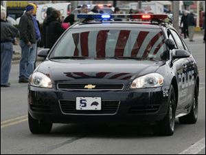 A giant American flag hung over the procession route for the funeral of police officer Andrew Dunn is reflected in the windshield of a Sandusky police car in March. 