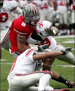 DeVier Posey is tackled by Jeremy Cash, front, and David Conor during Saturday’s scrimmage, which was won 59-27 by the Ohio State offense.