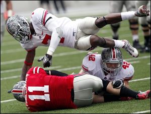 Tight end Jake Stoneburner is tackled by Travis Howard, top, and Andrew Sweat after making a catch.