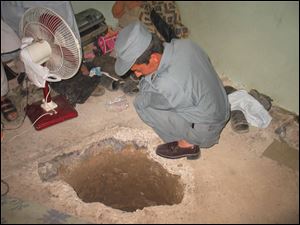 An Afghan police officer inspects the entrance to to an escape tunnel at the main prison in Kandahar, Afghanistan. 
